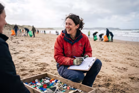 Outreach coordinator tallying finds at a volunteer beach cleanup — Person `main_image`, staff/engagement.