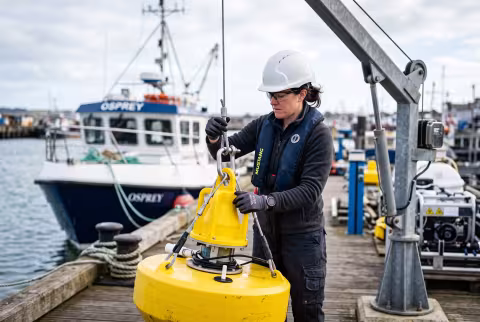 Instrumentation engineer guiding a monitoring buoy off the dock — Person `main_image`, staff/technical.