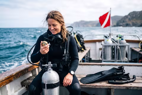 Scientific diving officer checking gear on a dive boat gunwale — Person `main_image`, staff/field.